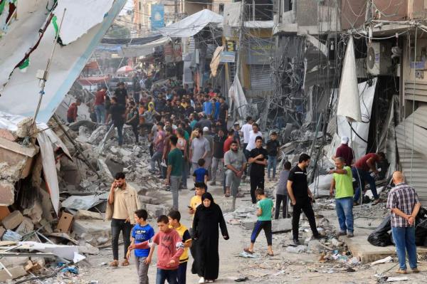 Palestinians walk amid the rubble of destroyed and damaged building